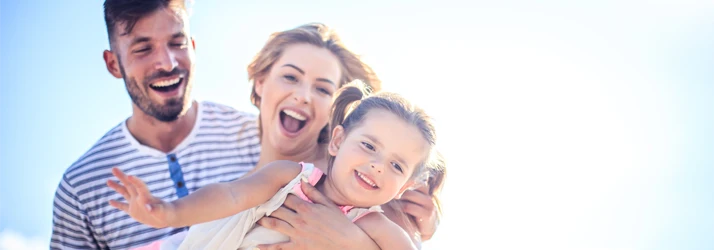 A family enjoying time outside under bright natural light with a clear sky background.